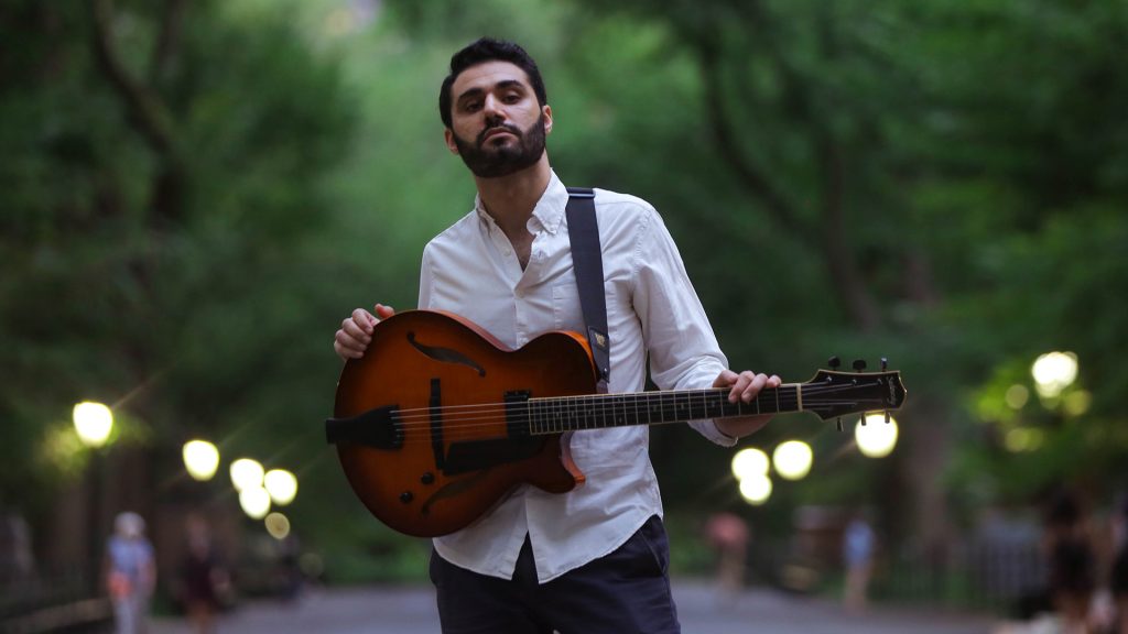 man holding guitar in park 