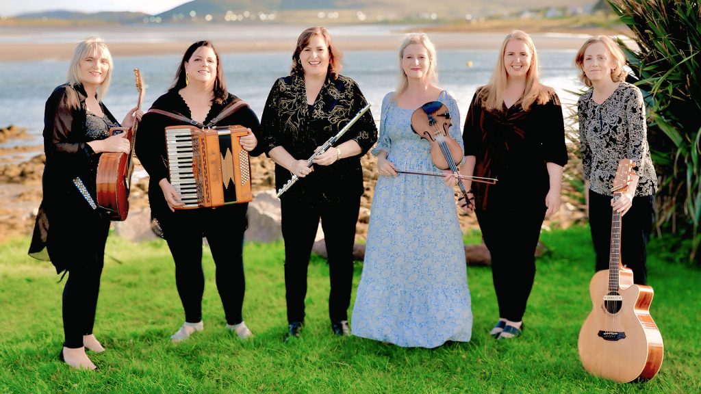 women holding musical instruments in front of lake