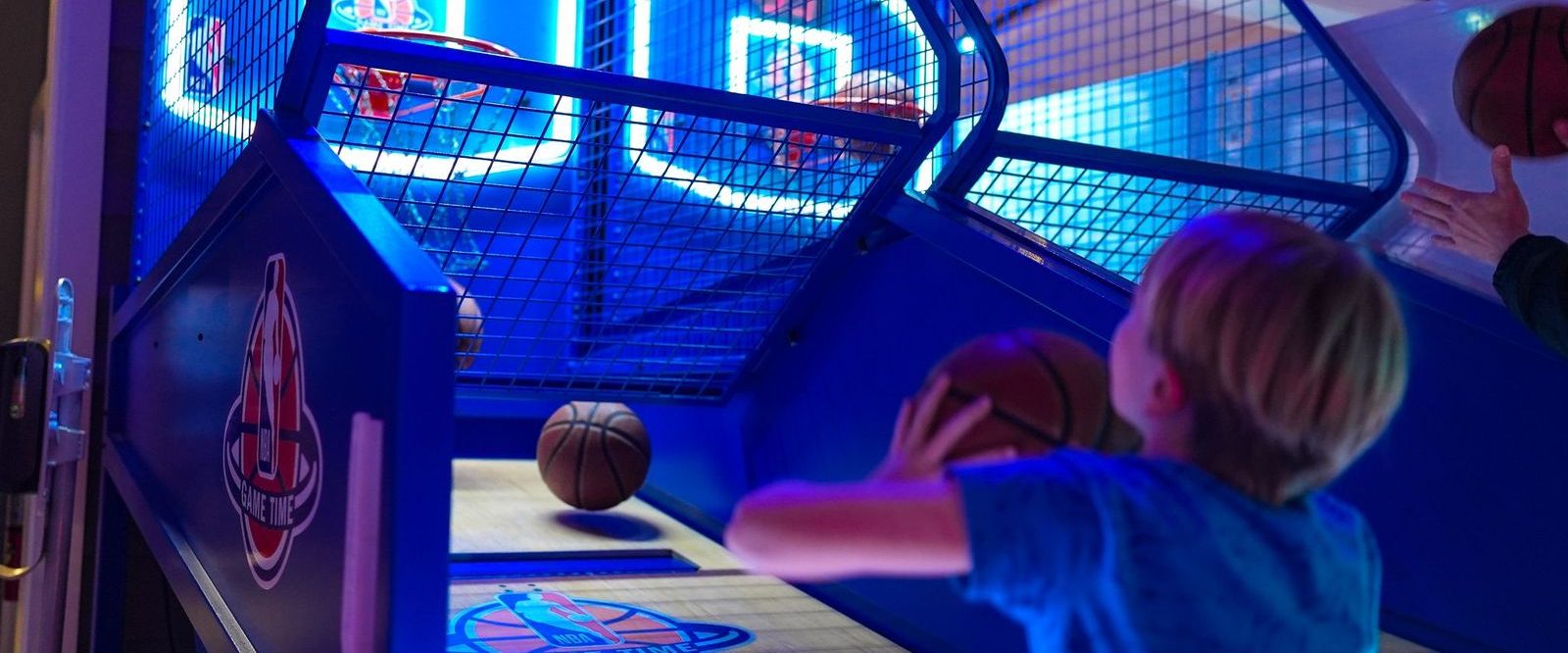 boy throwing basketball into hoop in arcade