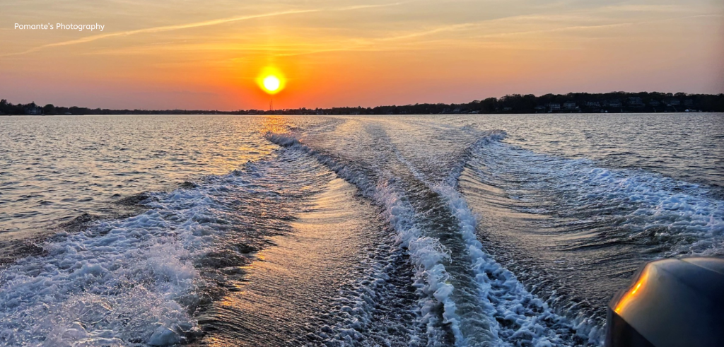 waves from a boat in the bay and a sunset