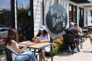 People sitting outside a coffee shop having coffee. How You Brewin Coffee Company