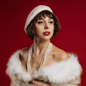 woman in a fur jacket with pearls around her neck and a white hat