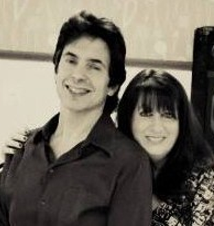Photo of a man and a woman with her arm around him