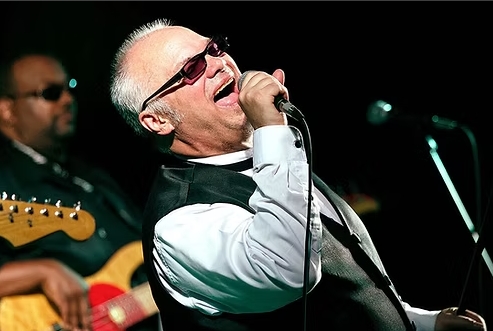 man in glasses singing into a microphone