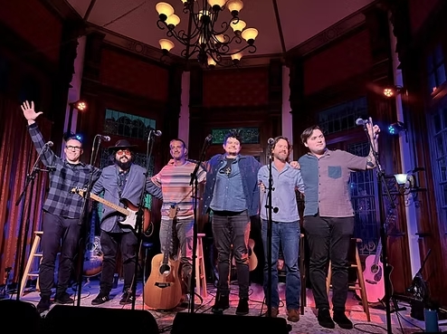Musicians standing on a stage posing for a photo together