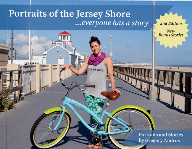 woman standing in front of a bicycle on a boardwalk by the ocean